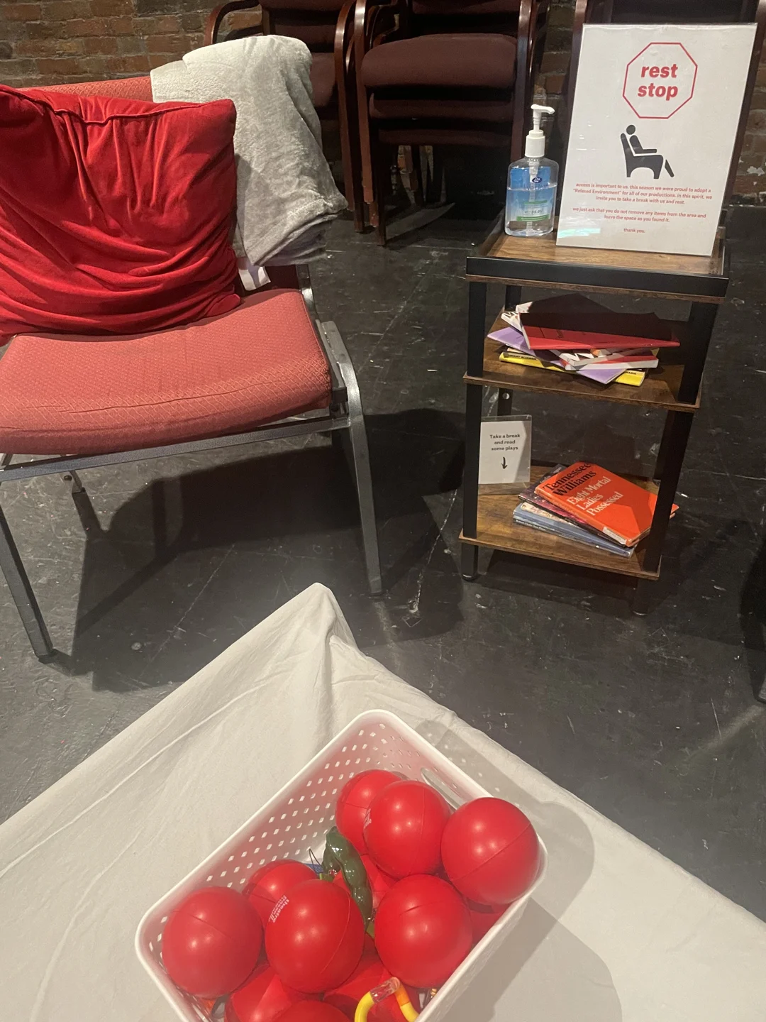 A red armchair, blanket and supplies at Theatre Passe Muraille’s 2025 rest space