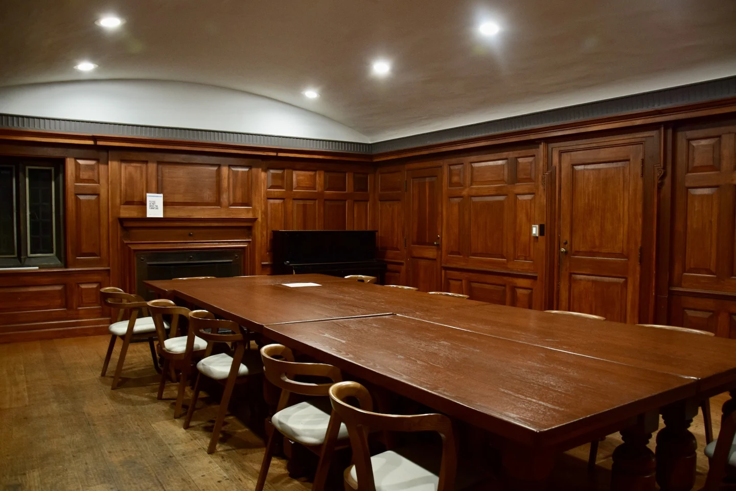 The wood-panelled Bickersteth Room has meeting tables and an upright piano against the wall