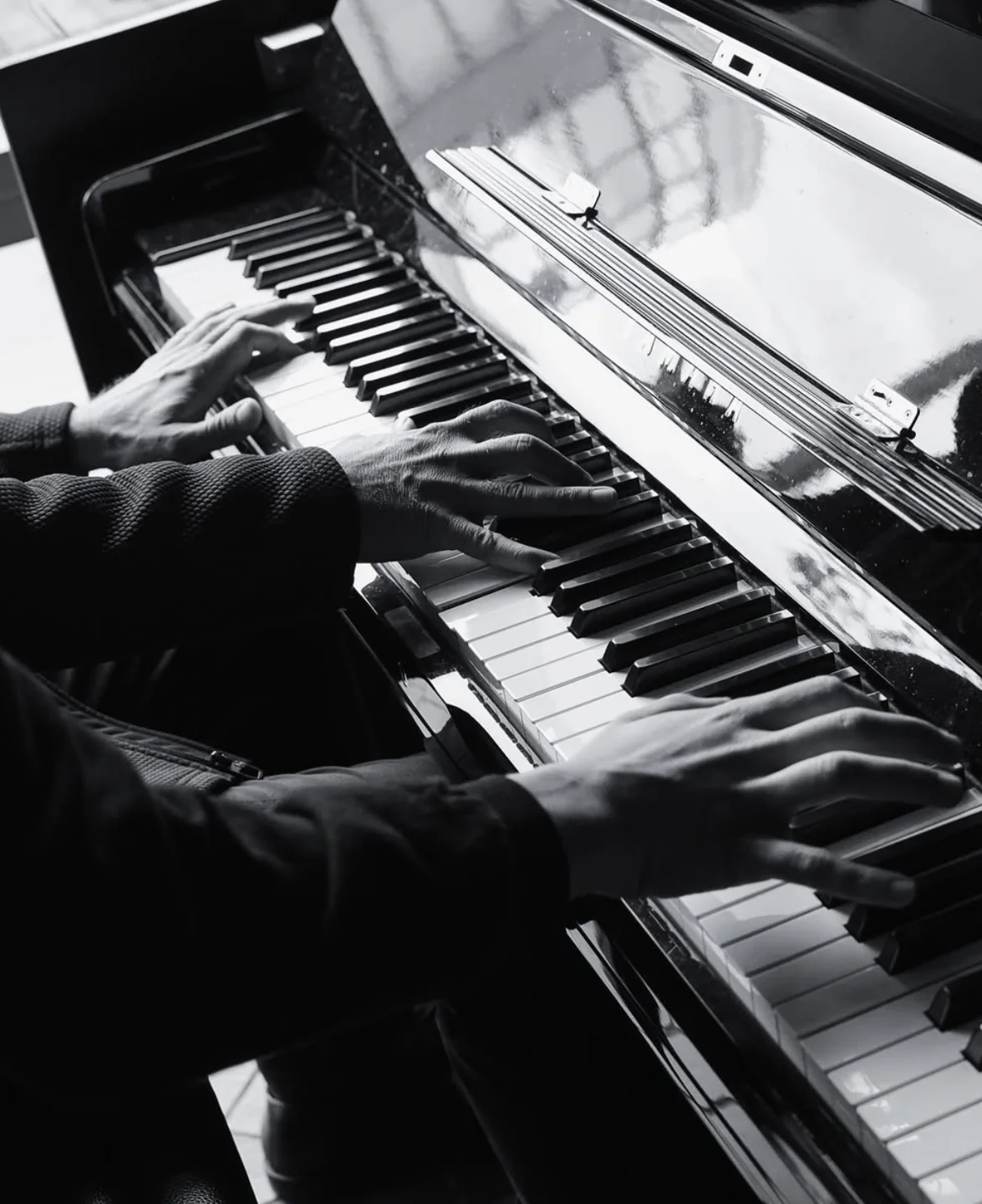 Hands play the upright piano beside The Painted Lady’s window