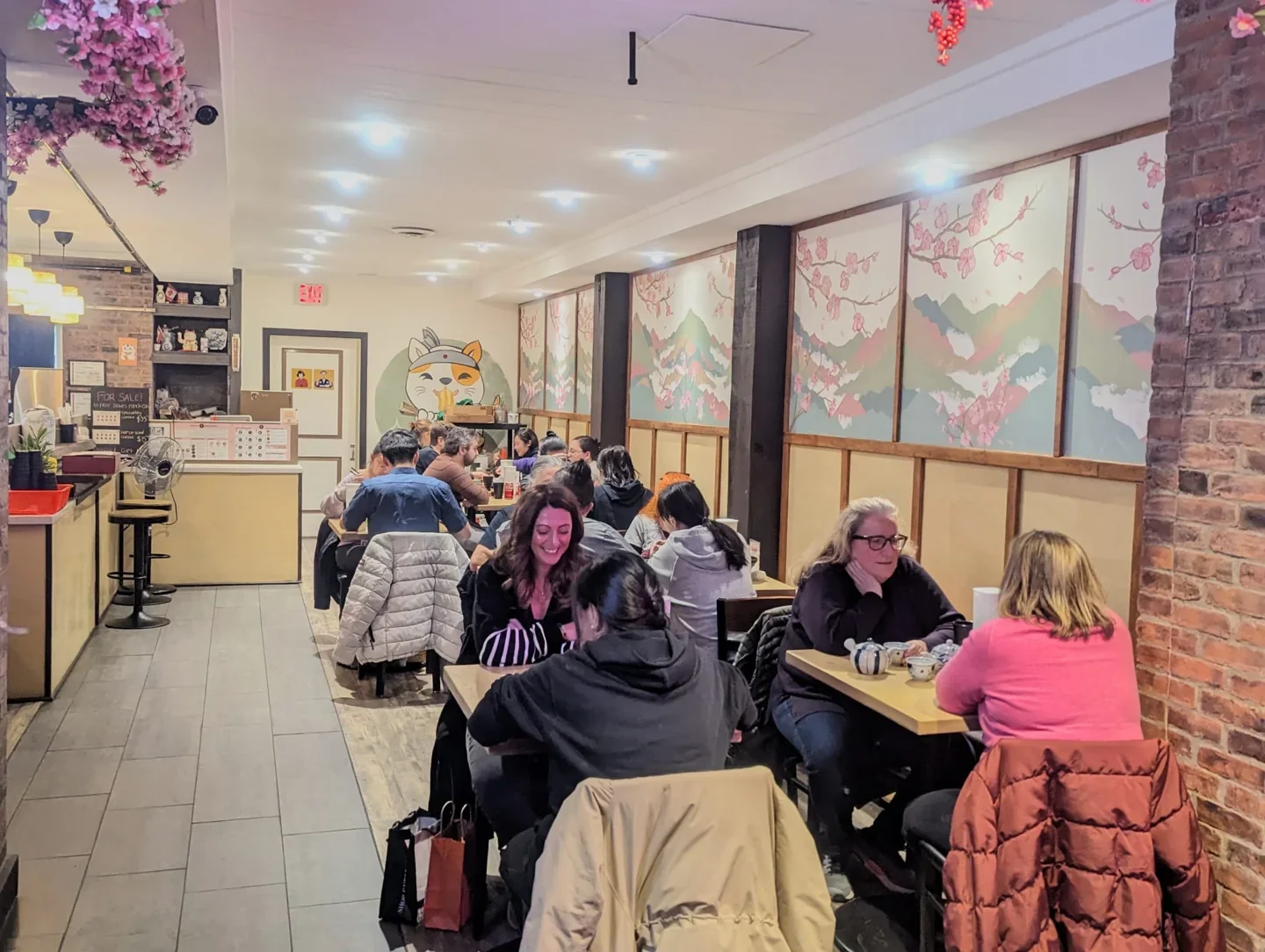 Diners seated at small tables inside Megumi Mazesoba