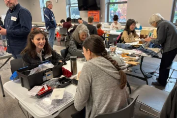 Volunteers and visitors work on clothing and small items at a Toronto Repair Café