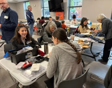 Volunteers and visitors work on clothing and small items at a Toronto Repair Café