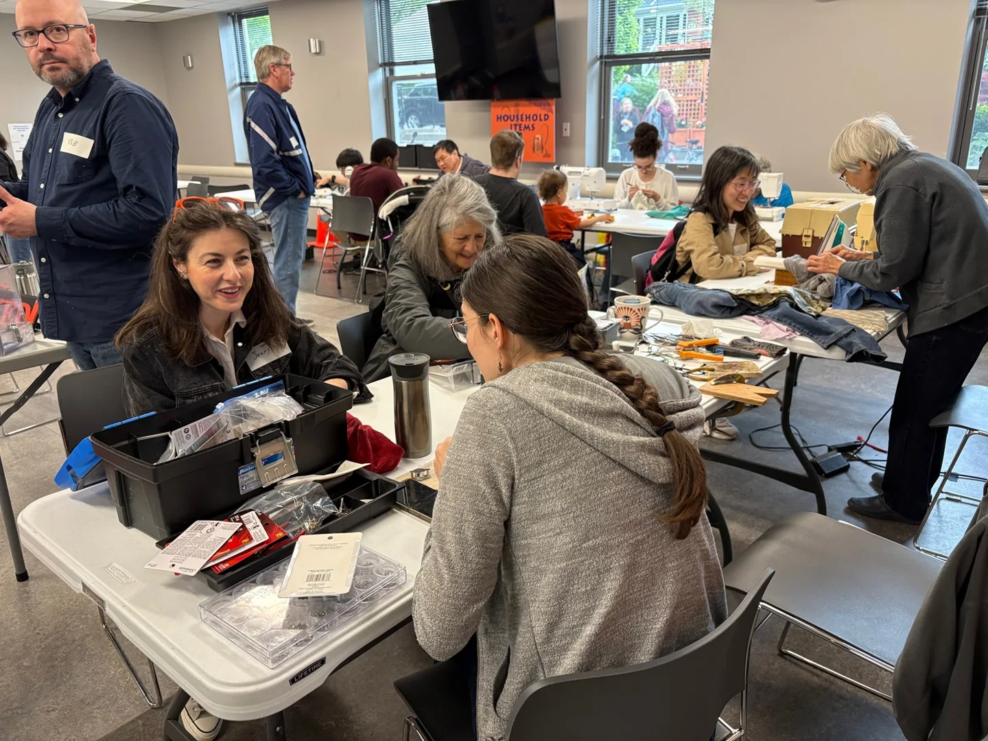 Volunteers and visitors work on clothing and small items at a Toronto Repair Café