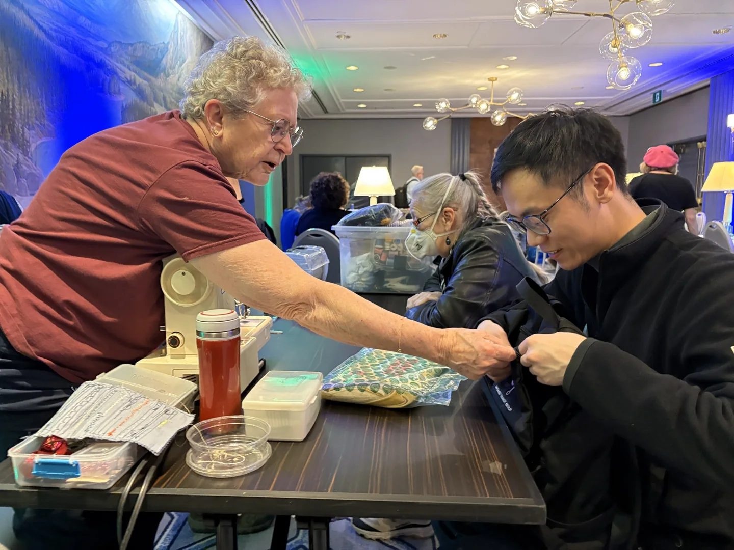 Two people work together at a sewing machine during a repair event