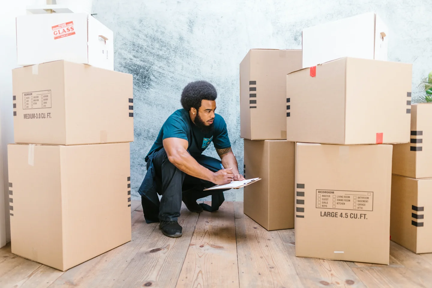 A person with a clipboard checks packed moving boxes
