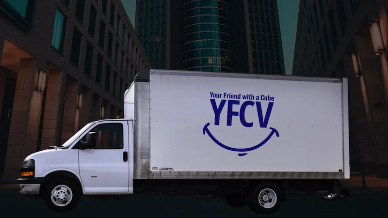 A Your Friend with a Cube Van moving truck parked by a building