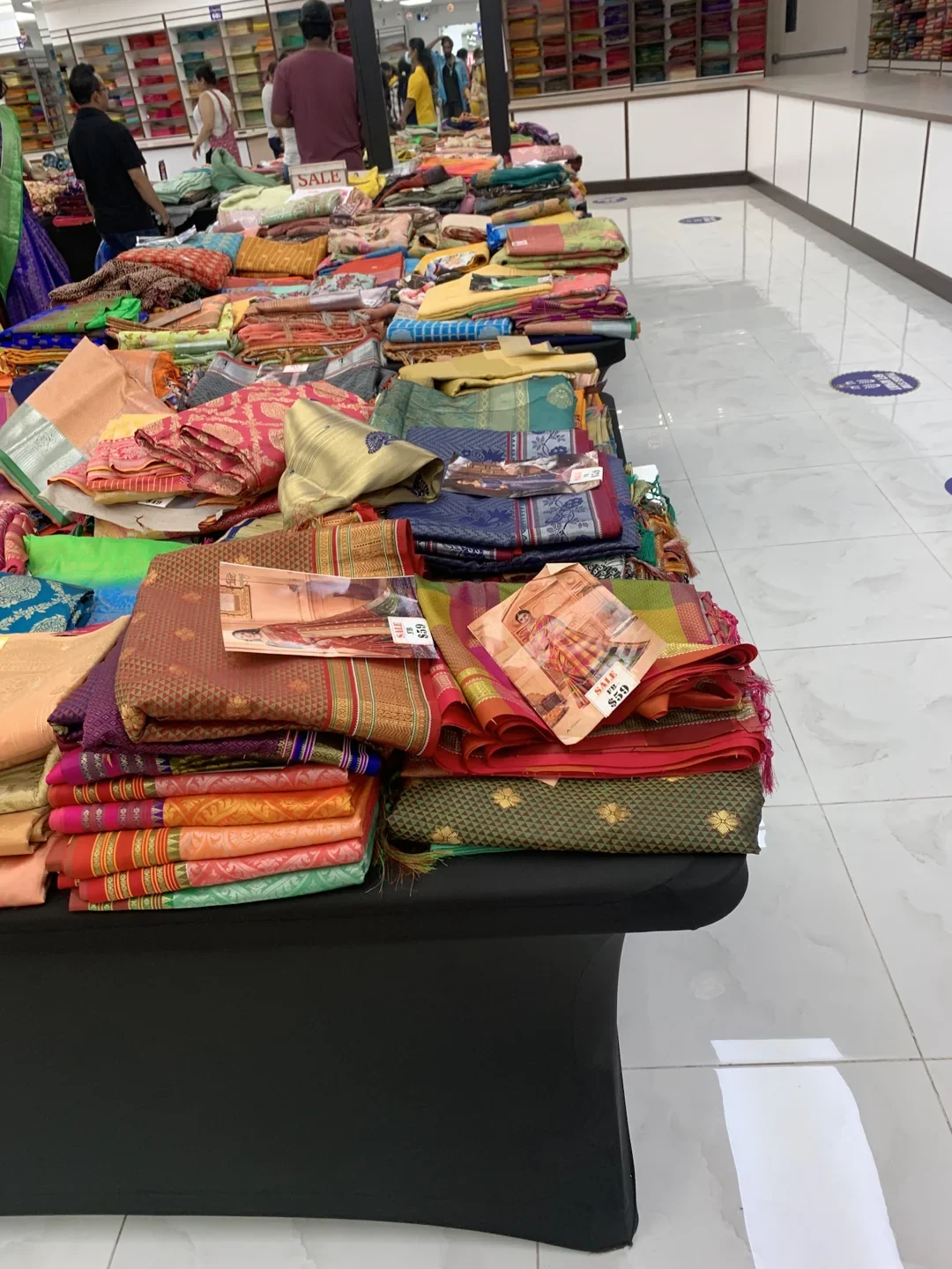 Colourful folded sarees on a display table at Asiyans in Scarborough