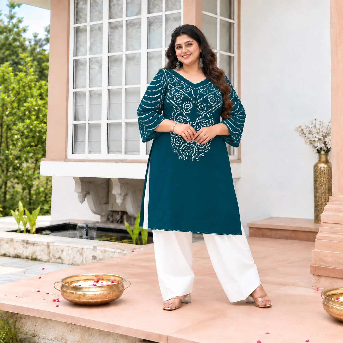 A model wearing a blue-green Meera’s outfit with white trousers