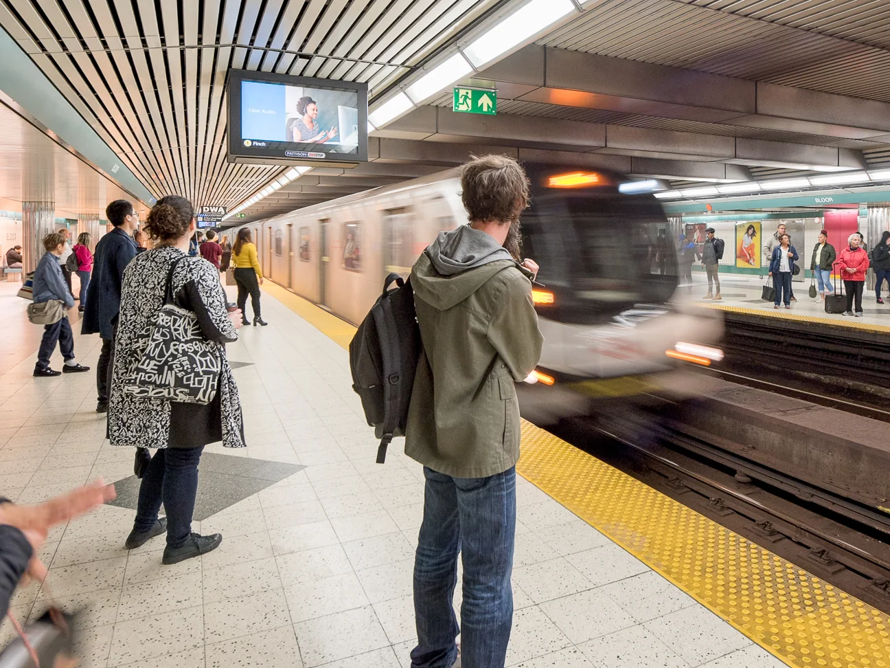 Riders wait behind the yellow platform strip as a TTC train arrives