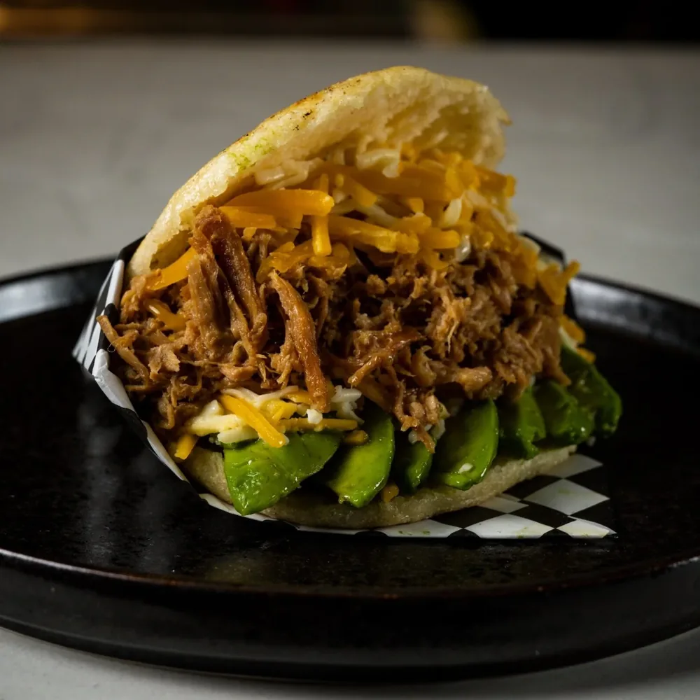 A filled arepa topped with grated cheese