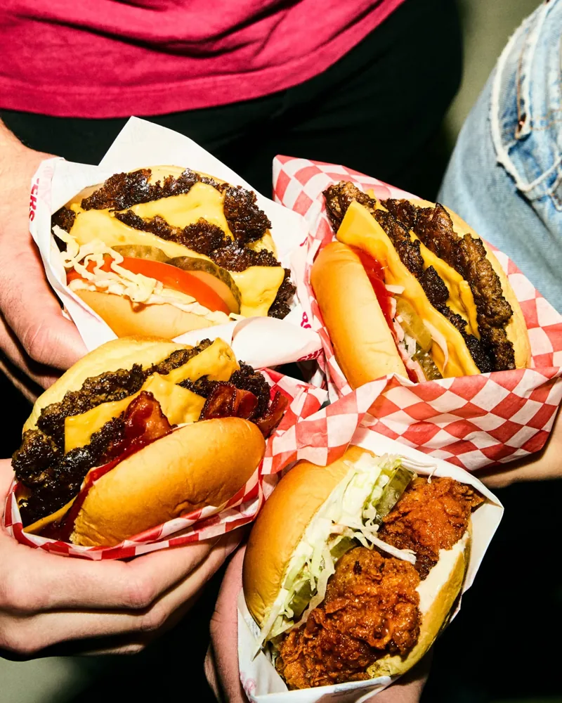 Friends hold burgers wrapped in Rosie’s paper