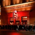 Concertgoers outside Massey Hall under its red neon sign