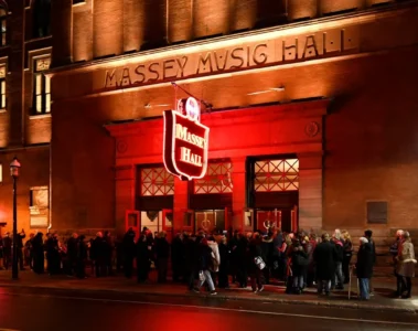 Concertgoers outside Massey Hall under its red neon sign