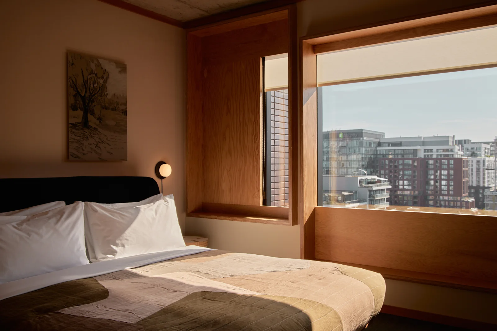 An Ace Hotel Toronto suite bedroom with a large window and a view across nearby rooftops