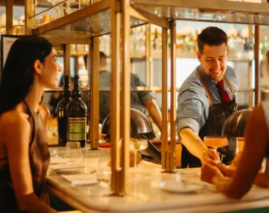 Two women sit at the bar while a bartender pours a drink at Four Seasons Hotel Toronto