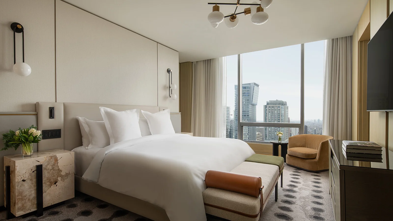 Bright Four Seasons Toronto guest room with a king bed and a chair beside the window