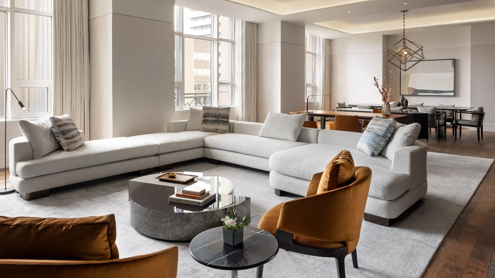 Curved white sofas, ochre chairs and tall windows in the Presidential Suite at Park Hyatt Toronto
