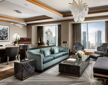 Teal sofa and armchairs beside floor-to-ceiling windows in the Wellington Suite at the Ritz-Carlton Toronto