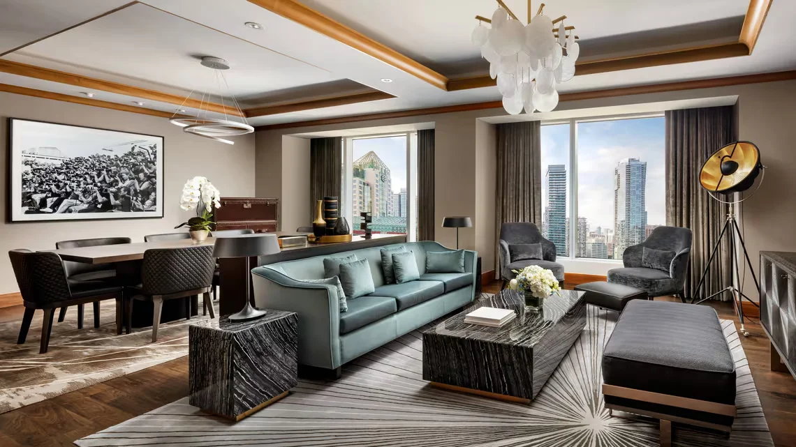 Teal sofa and armchairs beside floor-to-ceiling windows in the Wellington Suite at the Ritz-Carlton Toronto