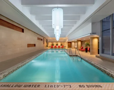 The long indoor pool at Shangri-La Toronto with red loungers at the far end