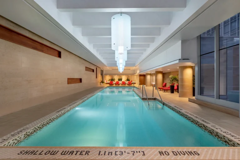 The long indoor pool at Shangri-La Toronto with red loungers at the far end