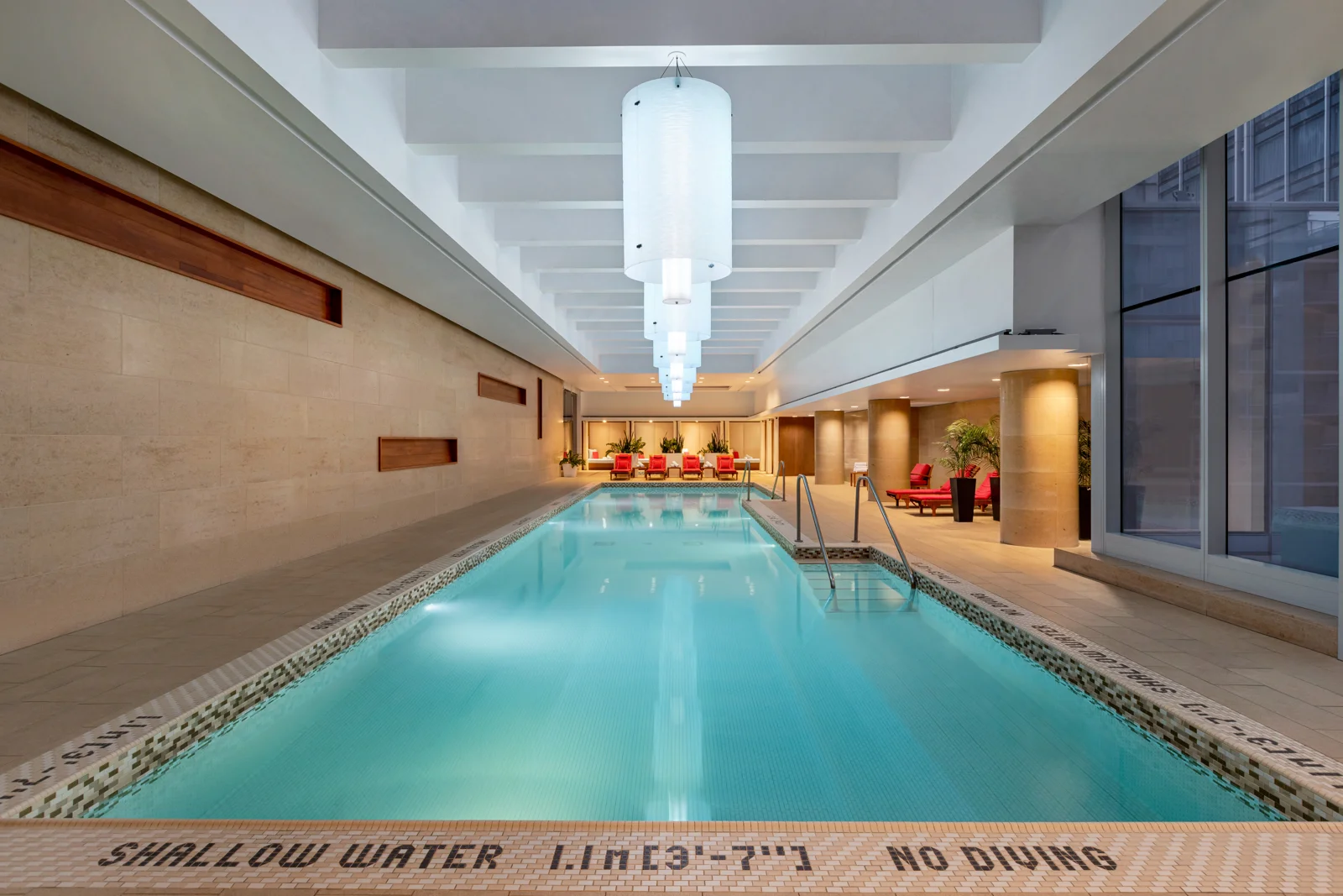 The long indoor pool at Shangri-La Toronto with red loungers at the far end
