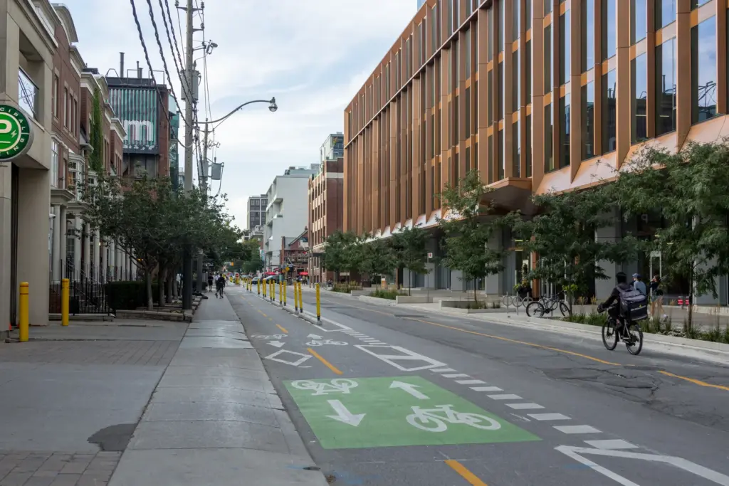 People cycling beside the separated bike lane on Portland Street in Toronto