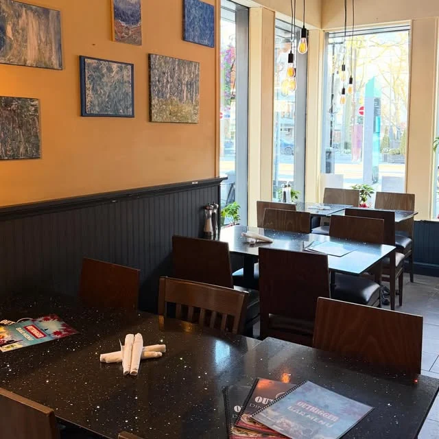 Tables beside a window and paintings inside Outrigger
