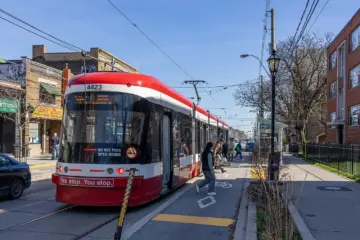 TTC streetcar stopped beside traffic on a Toronto street