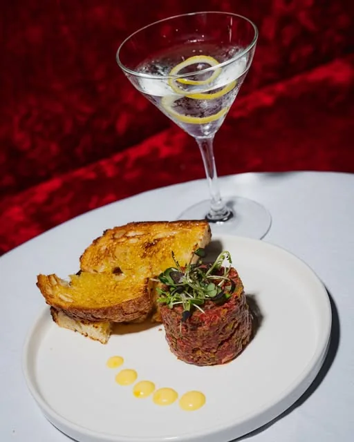 Steak tartare, toast and a martini on a table at Reservoir Lounge
