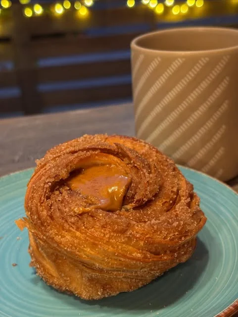 A pastry on a blue plate beside a mug at Savoury Grounds