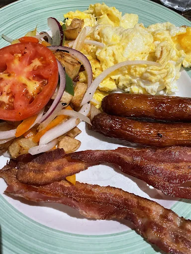Scrambled eggs, bacon, sausages and sliced vegetables at ViVetha Bistro