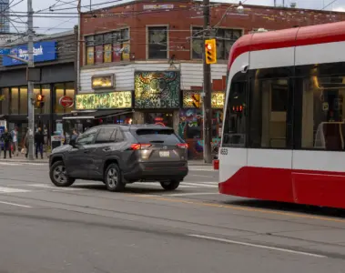 Modern TTC streetcar delayed behind a car making a left turn in Toronto