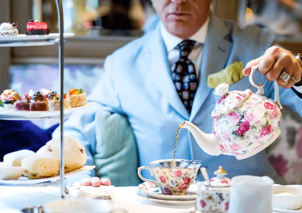 A server pours tea beside scones and a tiered stand of pastries at Windsor Arms