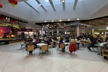 Crowded food court inside Woodside Square with red lanterns and many occupied tables