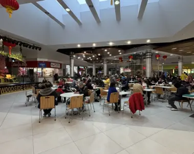 Crowded food court inside Woodside Square with red lanterns and many occupied tables