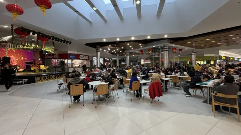 Crowded food court inside Woodside Square with red lanterns and many occupied tables
