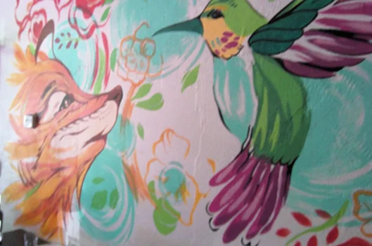A fox and hummingbird mural on a wall inside XOLA