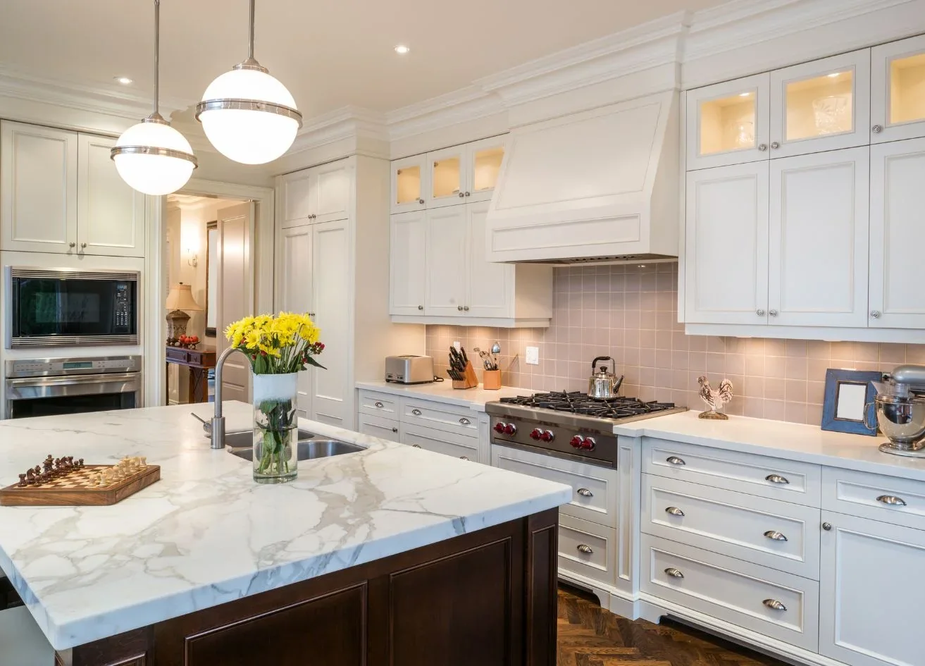Kitchen with white cabinet fronts, a cooktop and a stone island.