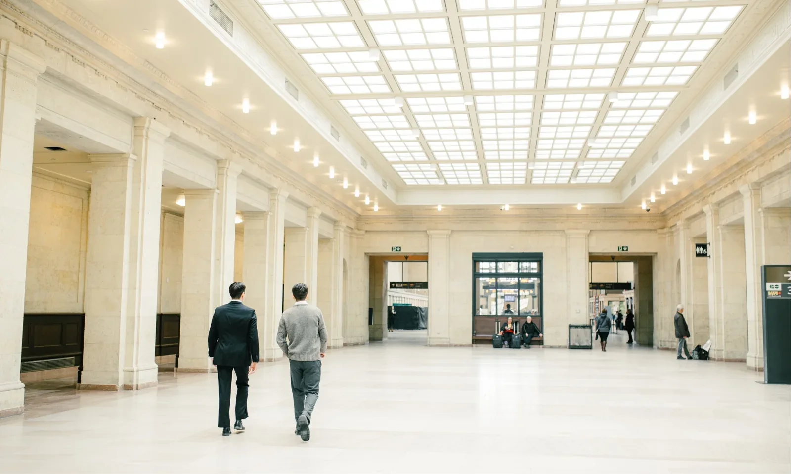 Two people walking through a bright hall at Union Station