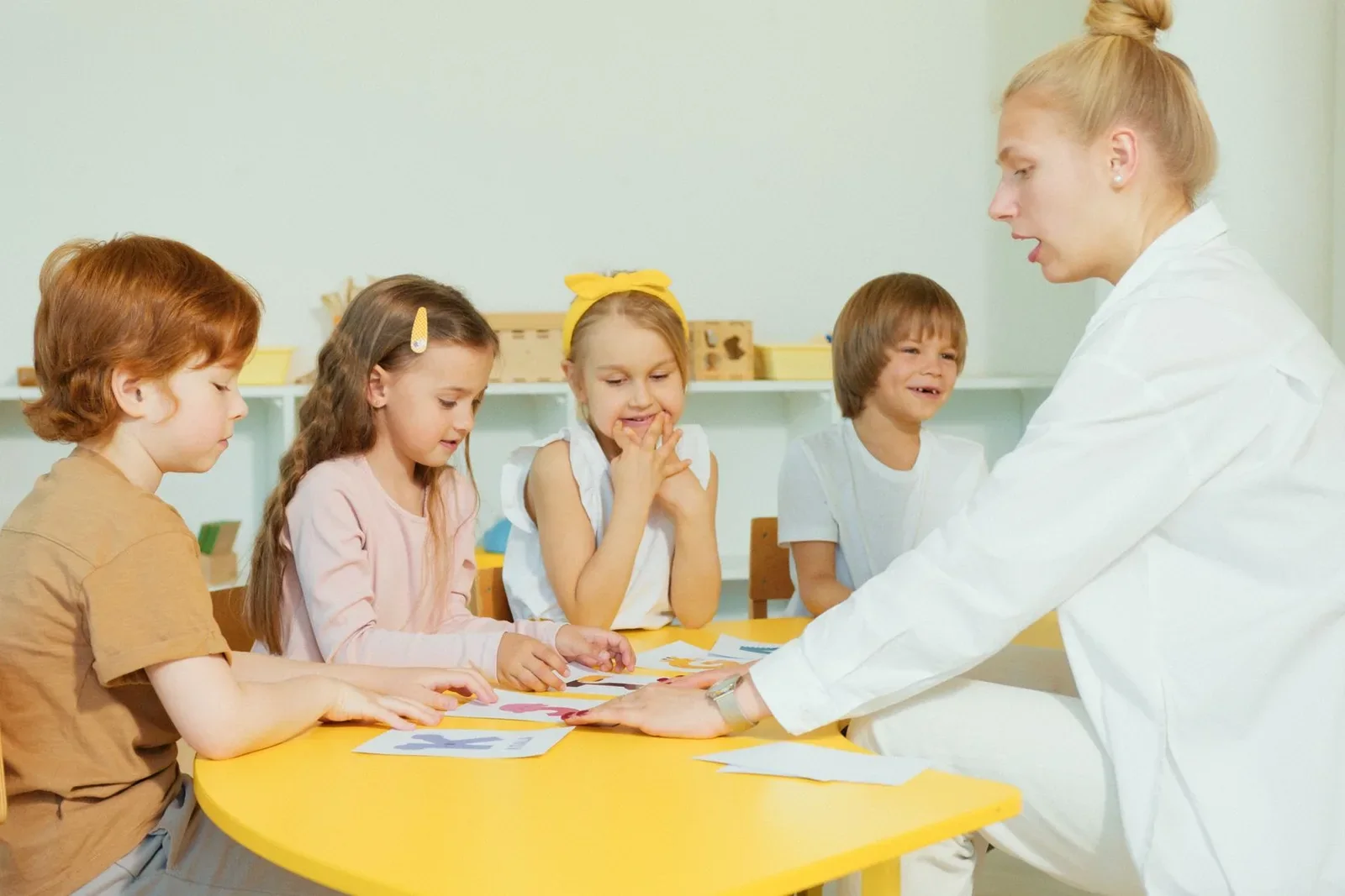 A teacher working with children at a classroom table