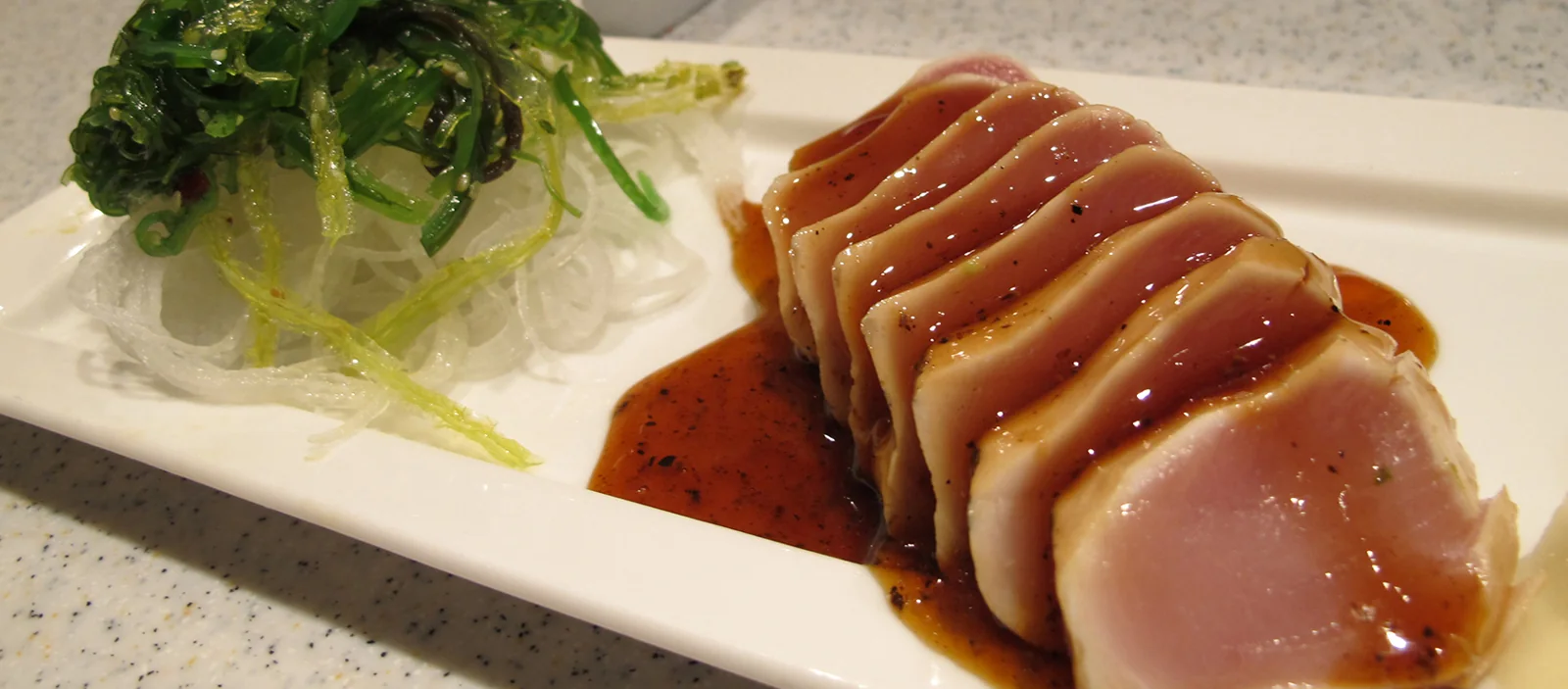 Sliced fish with sauce at Sushi California