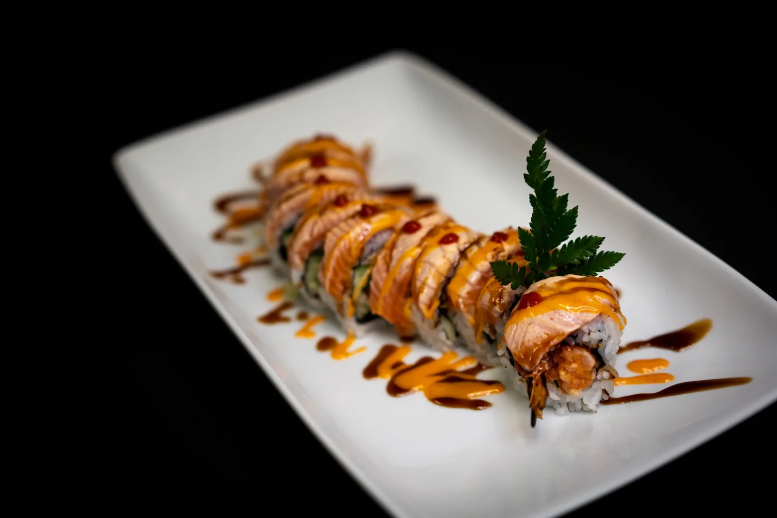 A topped sushi roll on a white plate at Hiroi Sushi