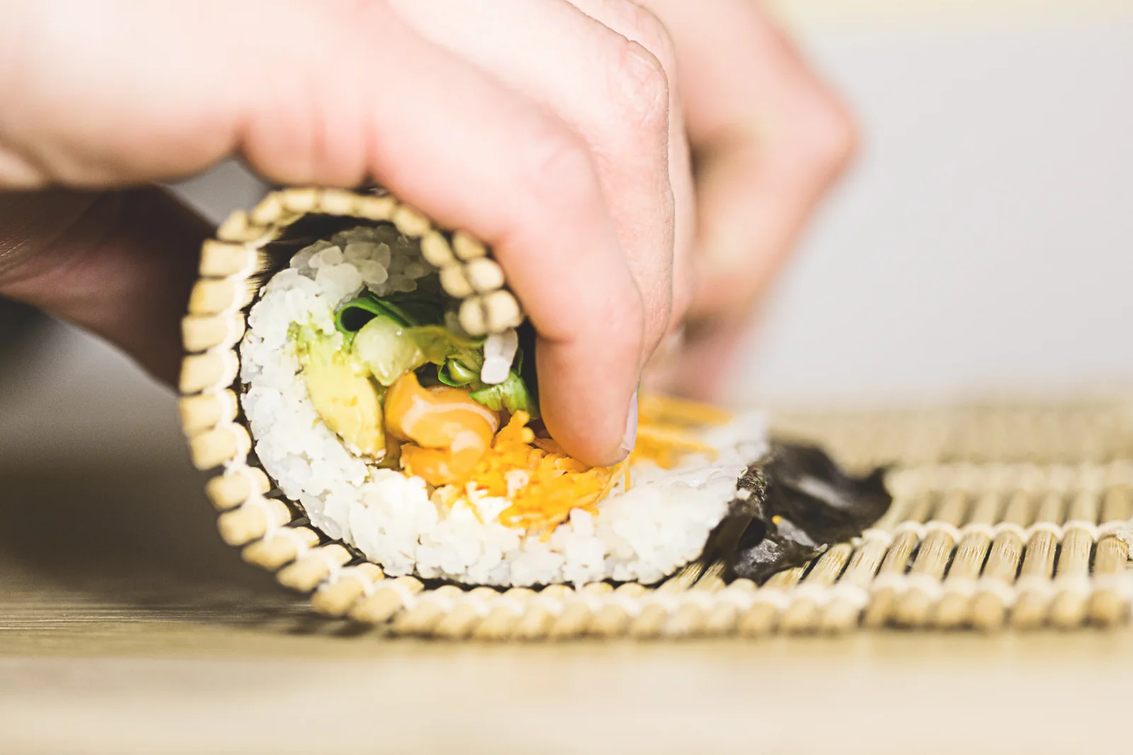 Hands preparing a sushi roll at Sushi Run