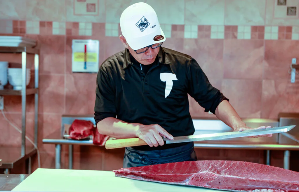A fishmonger preparing a large piece of fish at Taro’s Fish