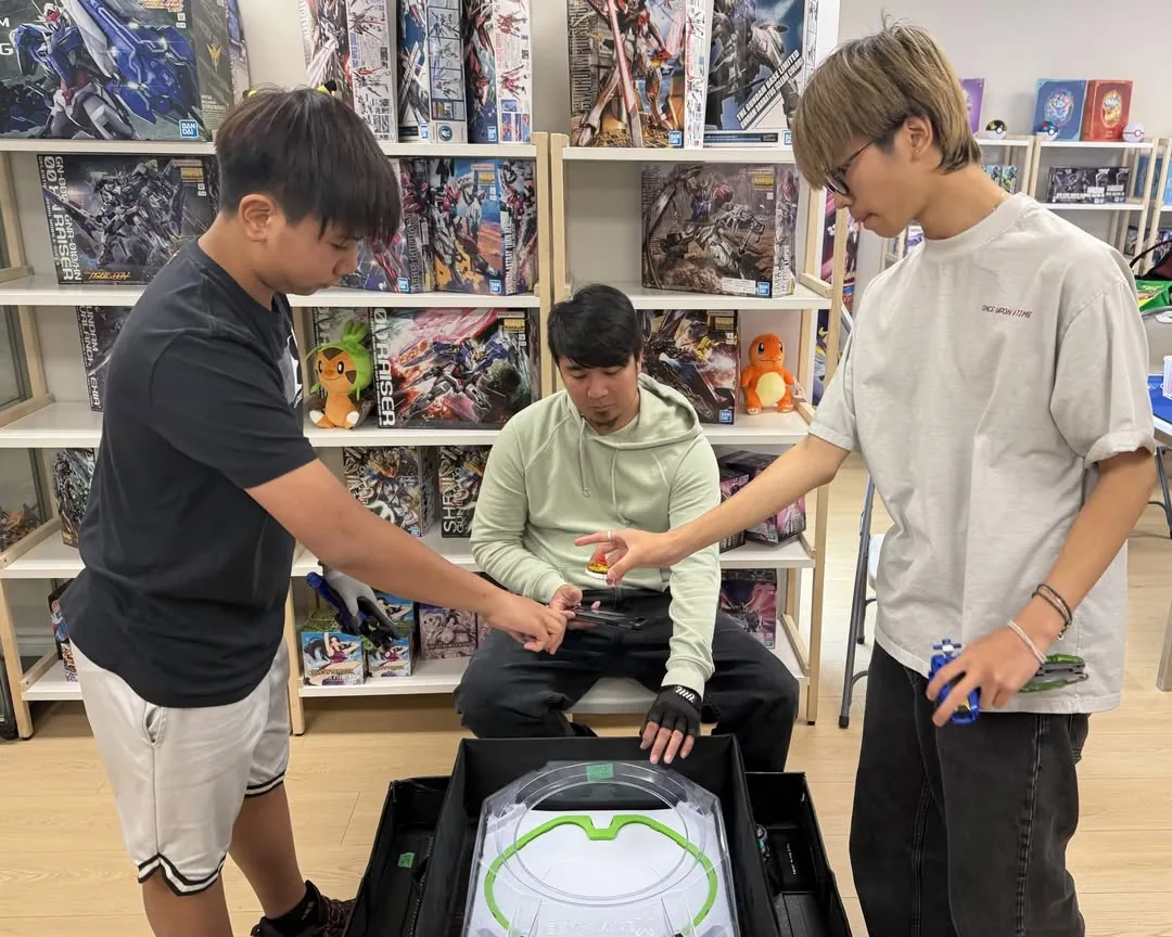 Two players launching tops into a stadium at Claw Me Baby Games