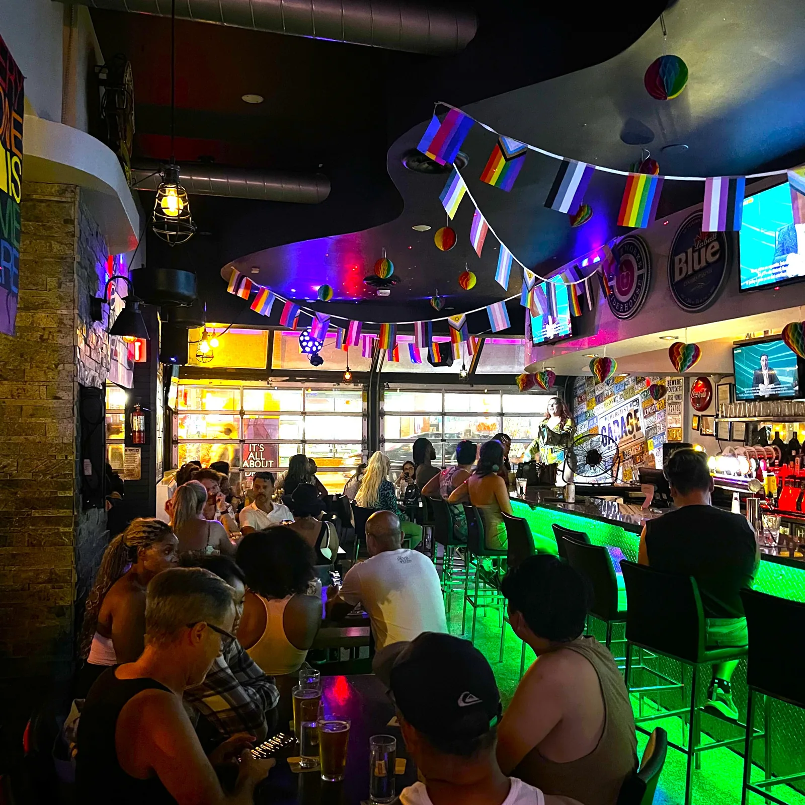 Patrons seated inside Church St. Garage beneath rainbow flags