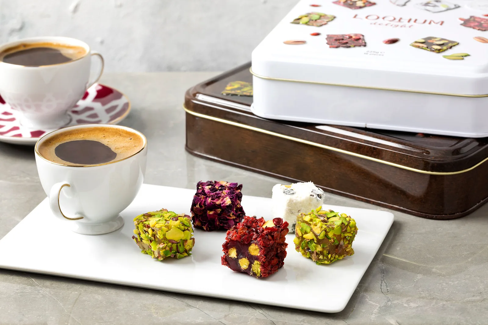 Two cups of coffee and pieces of Turkish delight beside decorative tins