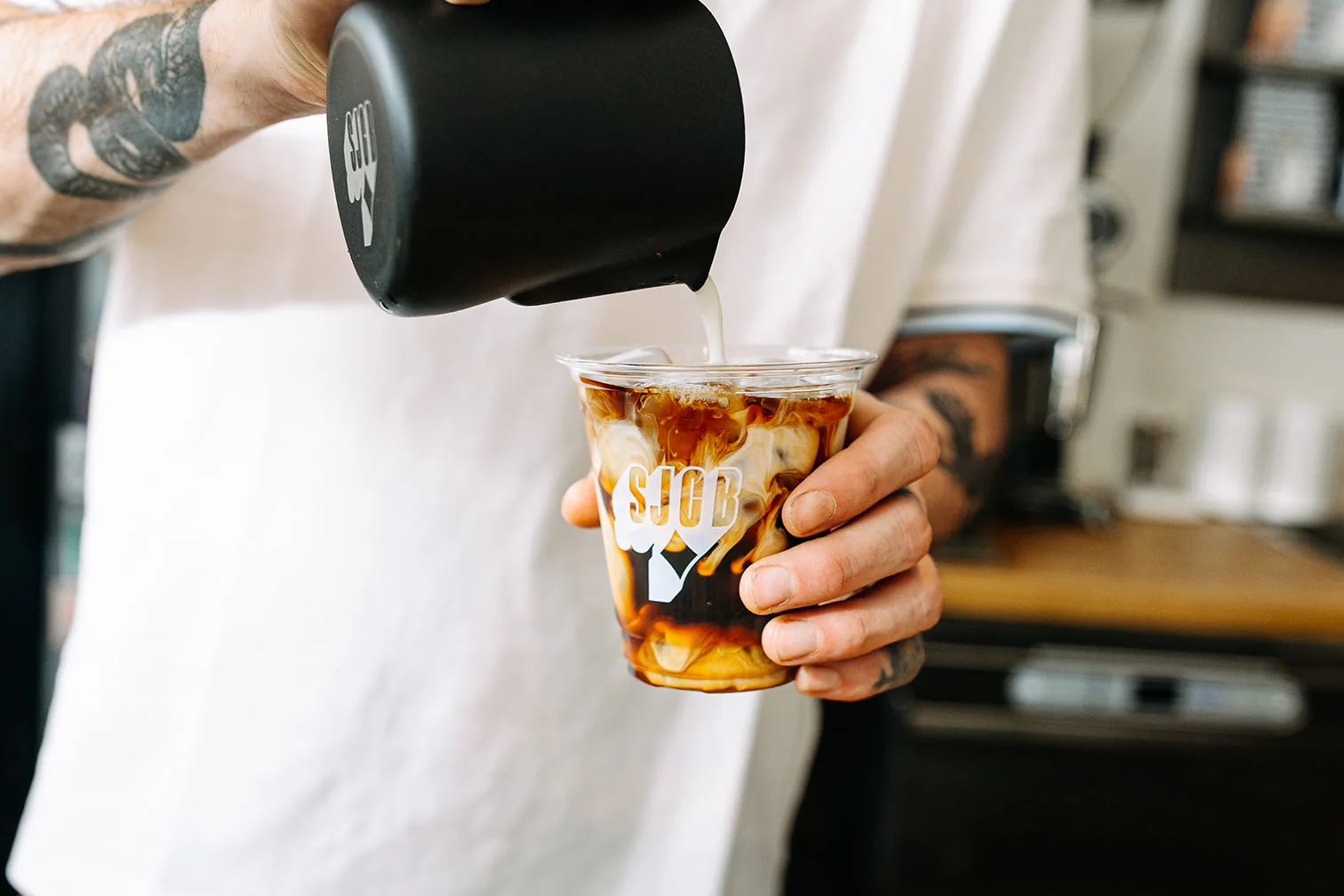 Milk being poured into an iced coffee at Sam James Coffee Bar