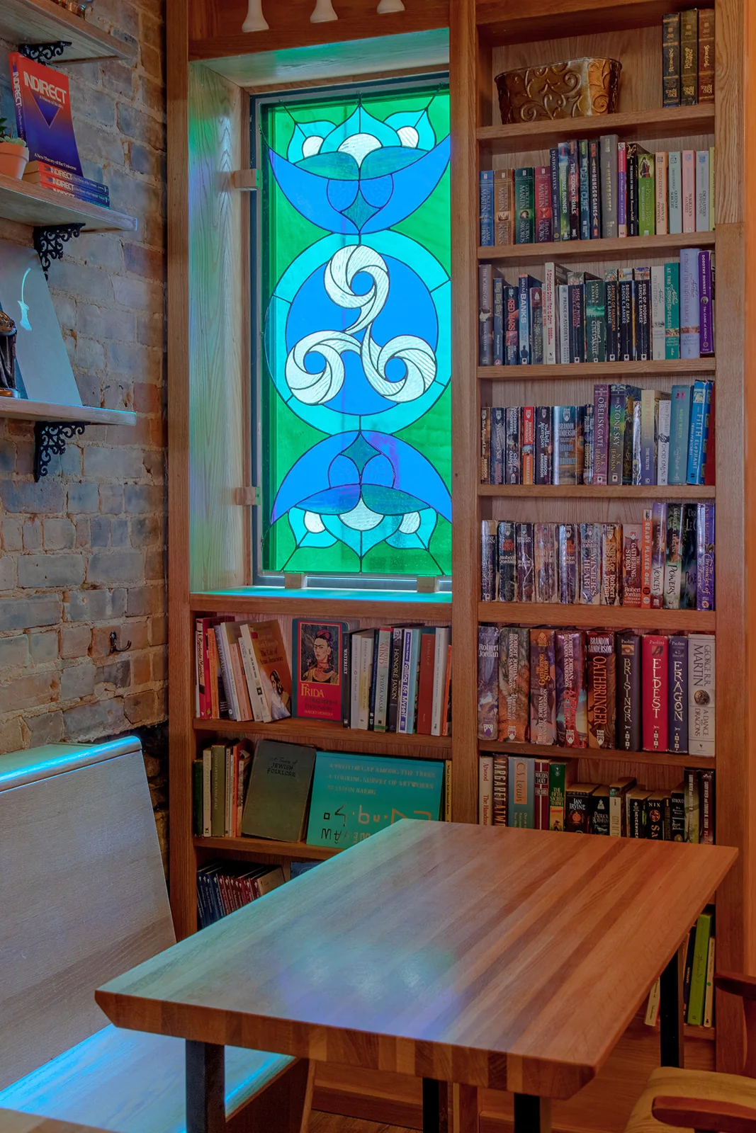 Stained glass window and bookshelves inside Danu Social House